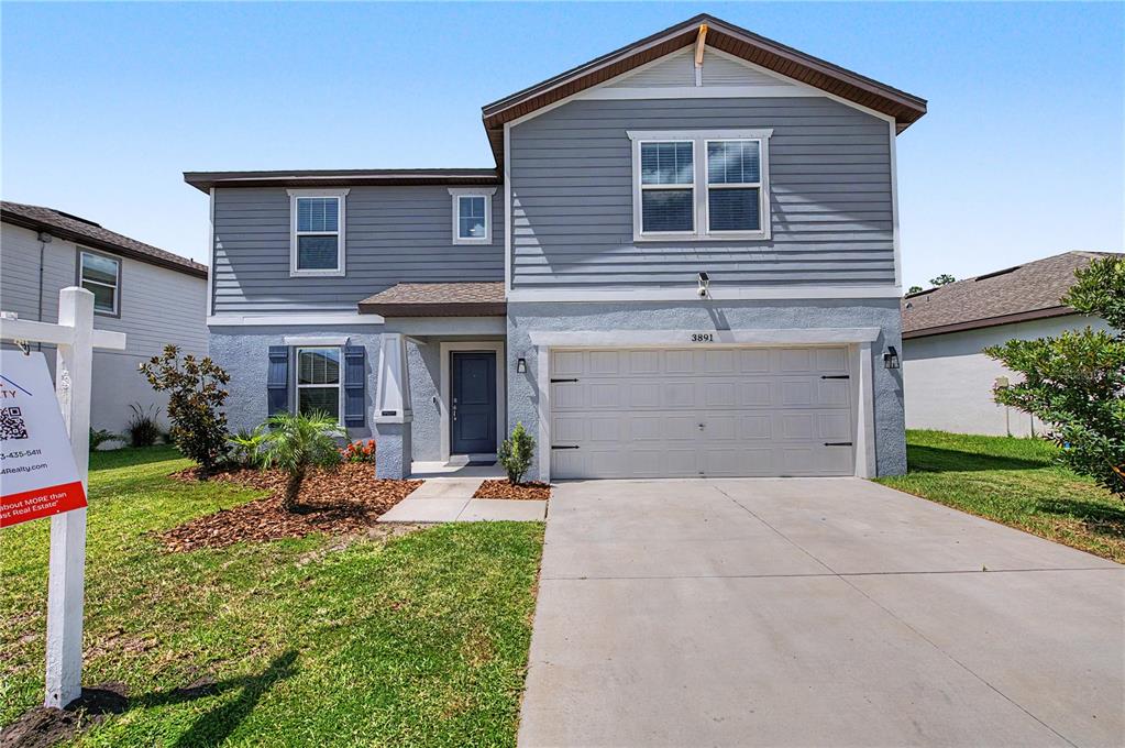 A two-story house with gray siding and stucco features a two-car garage and front lawn — 3891 CAPRI COAST DRIVE, PLANT CITY, FL