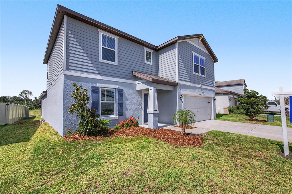 A two-story house with blue siding and stucco features a front porch and garage — 3891 CAPRI COAST DRIVE, PLANT CITY, FL