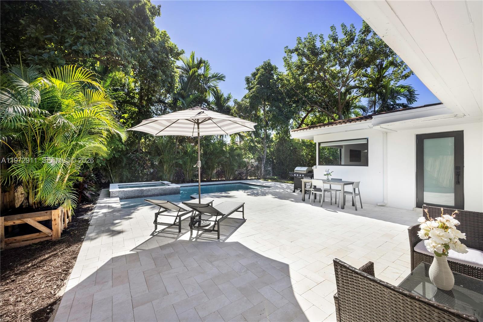 A backyard patio features a swimming pool, lounge chairs, a dining set, and lush landscaping — 1860 SW 13th St, Miami FL 33145, MIAMI, FL
