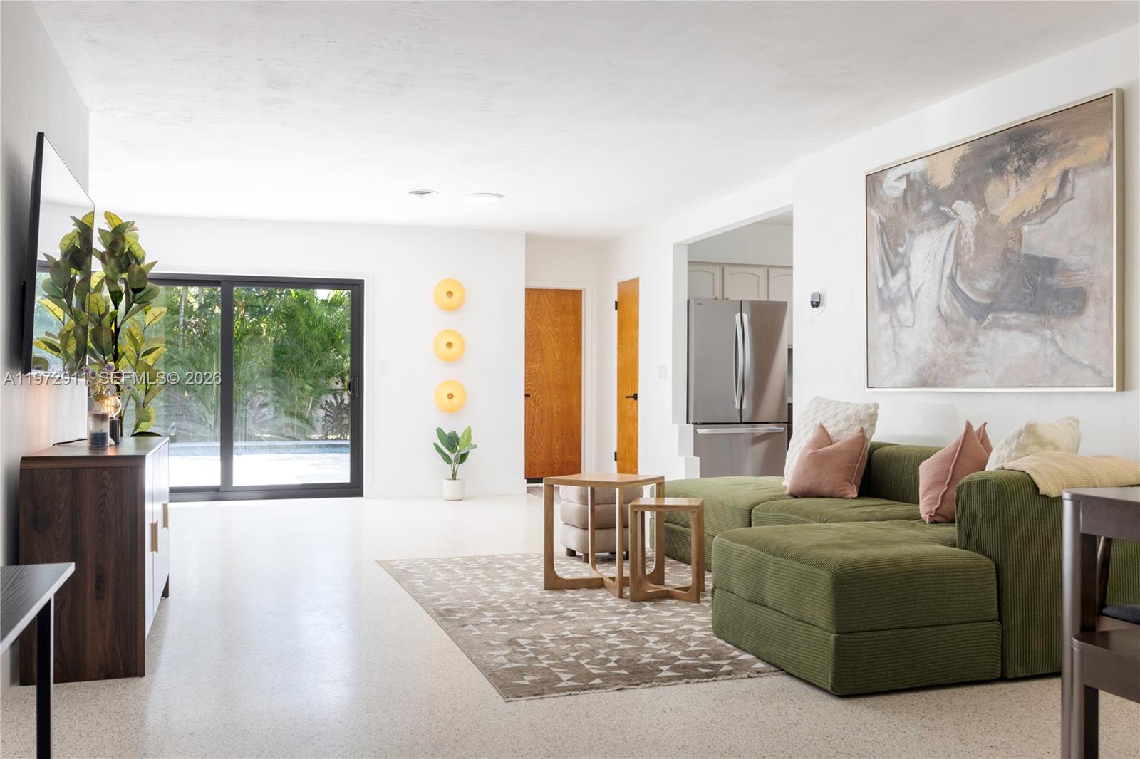 A living room features a green sectional sofa, a patterned rug, and a sliding glass door — 1860 SW 13th St, Miami FL 33145, MIAMI, FL