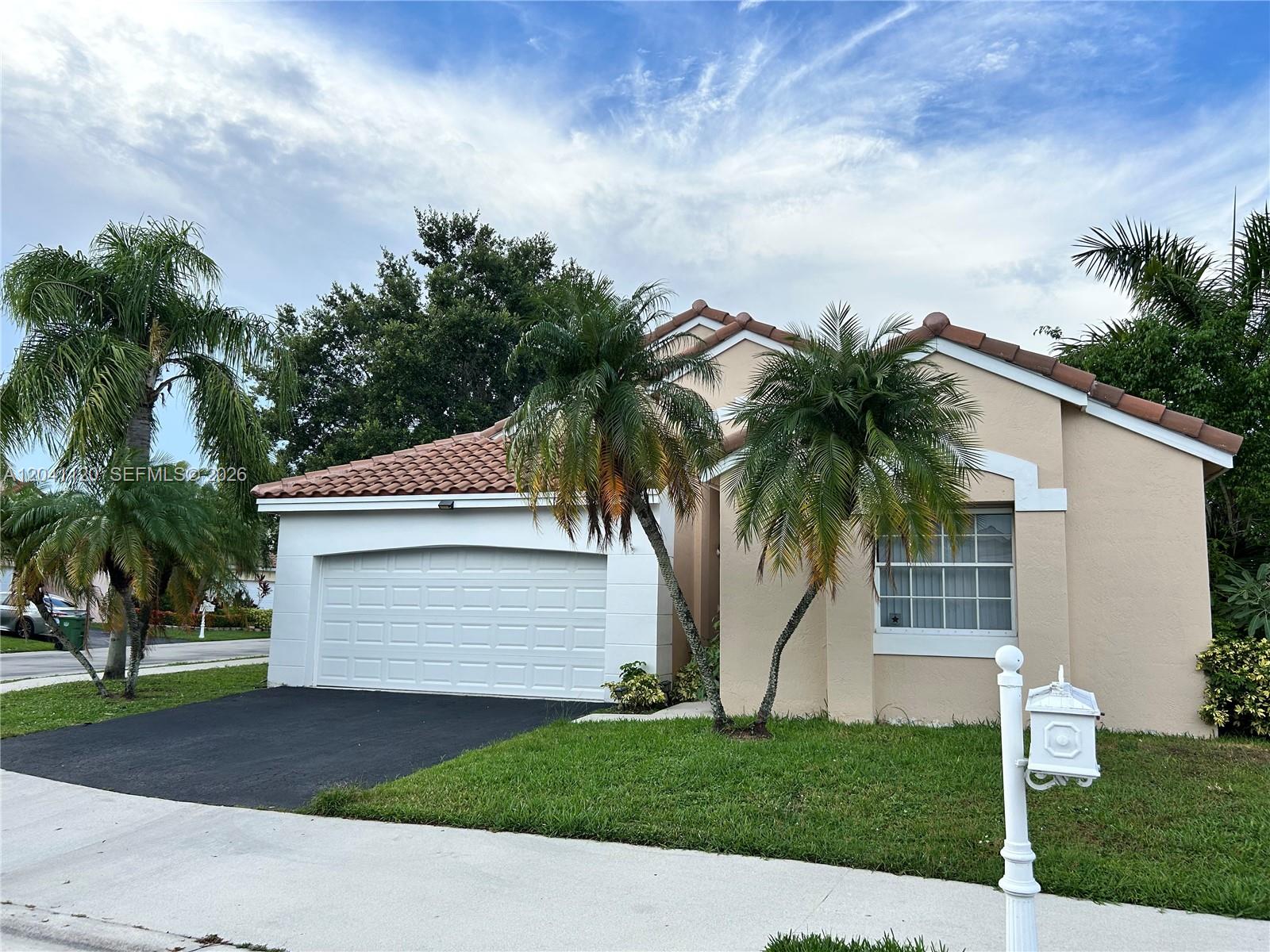 A single-story house with a tan exterior, tile roof, two-car garage, and front yard palms — 286 Bridgeton Way, Weston FL 33326, WESTON, FL
