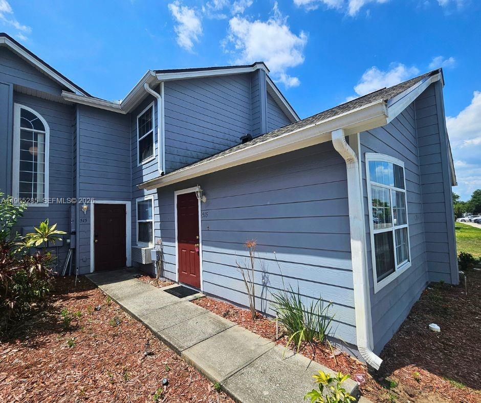 The exterior of a two-story blue-sided building features a concrete walkway and two red doors — 515 ORCHID DR, Davenport FL 33897, DAVENPORT, FL