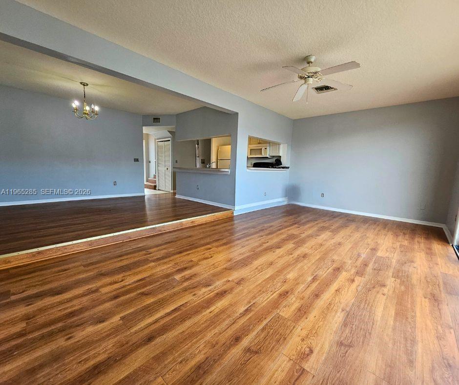 An open-concept living area features wood-look flooring, a ceiling fan, and a kitchen pass-through window — 515 ORCHID DR, Davenport FL 33897, DAVENPORT, FL