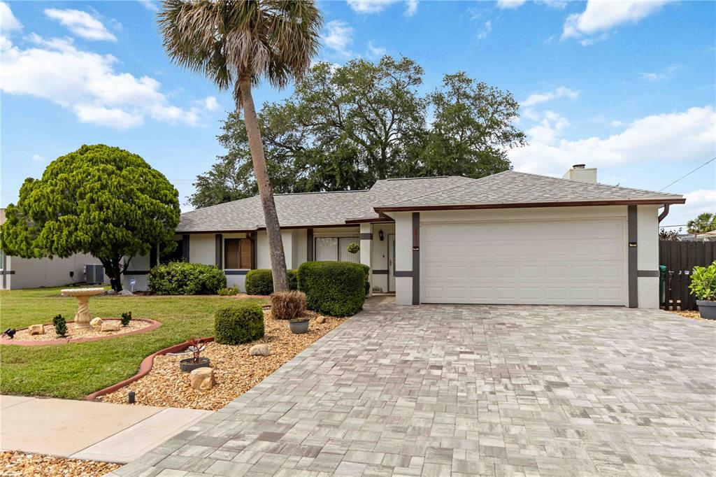 A single-story house features a paved driveway, a palm tree, and a landscaped front yard — 2415 RAINTREE LAKE CIRCLE, MERRITT ISLAND, FL