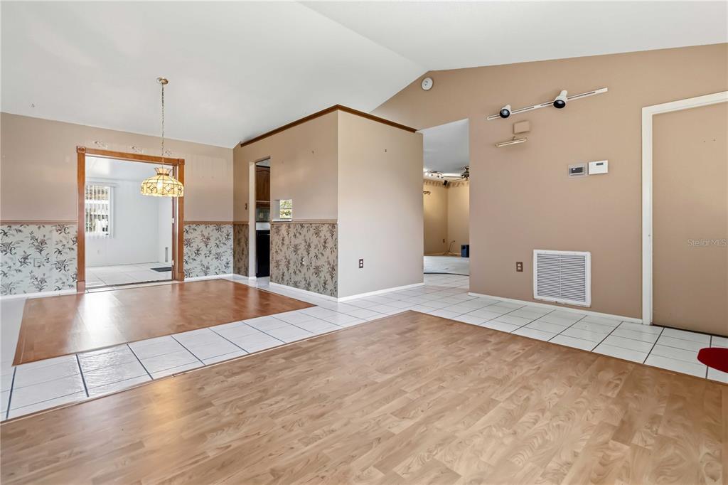 An interior view shows a living area with wood-look flooring, tiled sections, and wallpapered walls — 2415 RAINTREE LAKE CIRCLE, MERRITT ISLAND, FL