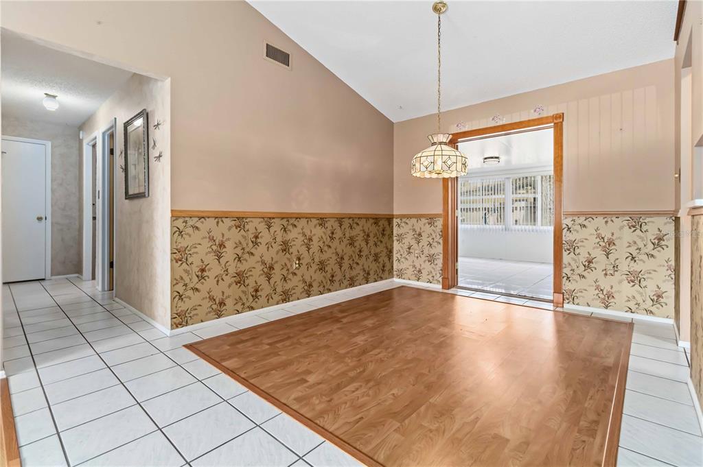 A dining area features wood flooring, floral wallpaper, a pendant light, and a sliding glass door — 2415 RAINTREE LAKE CIRCLE, MERRITT ISLAND, FL