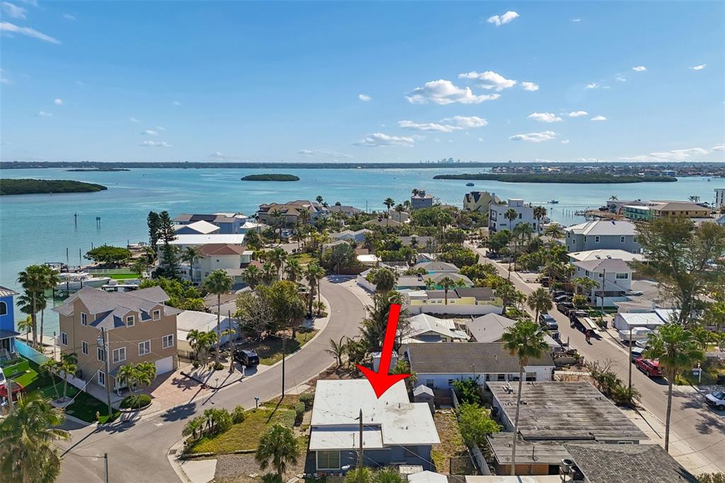 An aerial view shows a coastal neighborhood with a red arrow pointing to a house — 13098 BOCA CIEGA AVENUE, MADEIRA BEACH, FL