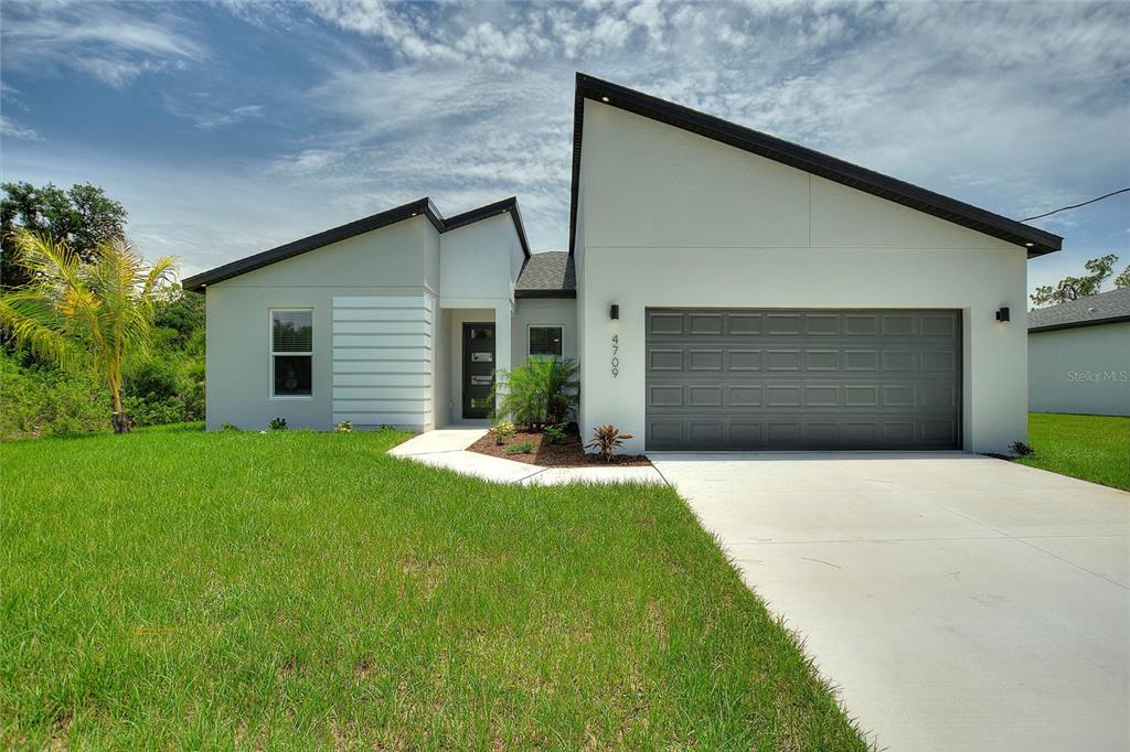A modern single-story house features a gray garage, white stucco exterior, and a paved driveway — 24459 SW KINGSWAY CIRCLE, ARCADIA, FL