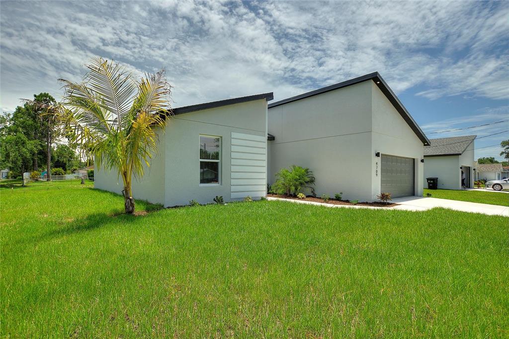 A modern, light-gray house with a flat roof and a palm tree in the yard — 24459 SW KINGSWAY CIRCLE, ARCADIA, FL