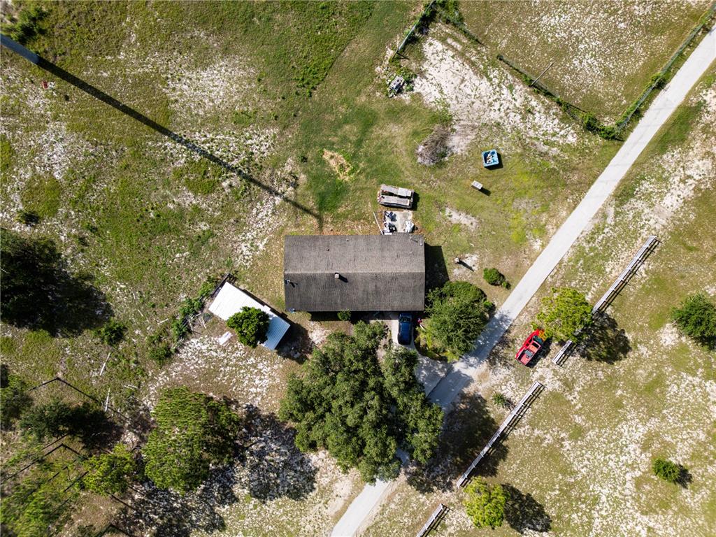 An aerial view shows a house with a metal shed and a driveway on land — 5555 E HINSON AVENUE, HAINES CITY, FL