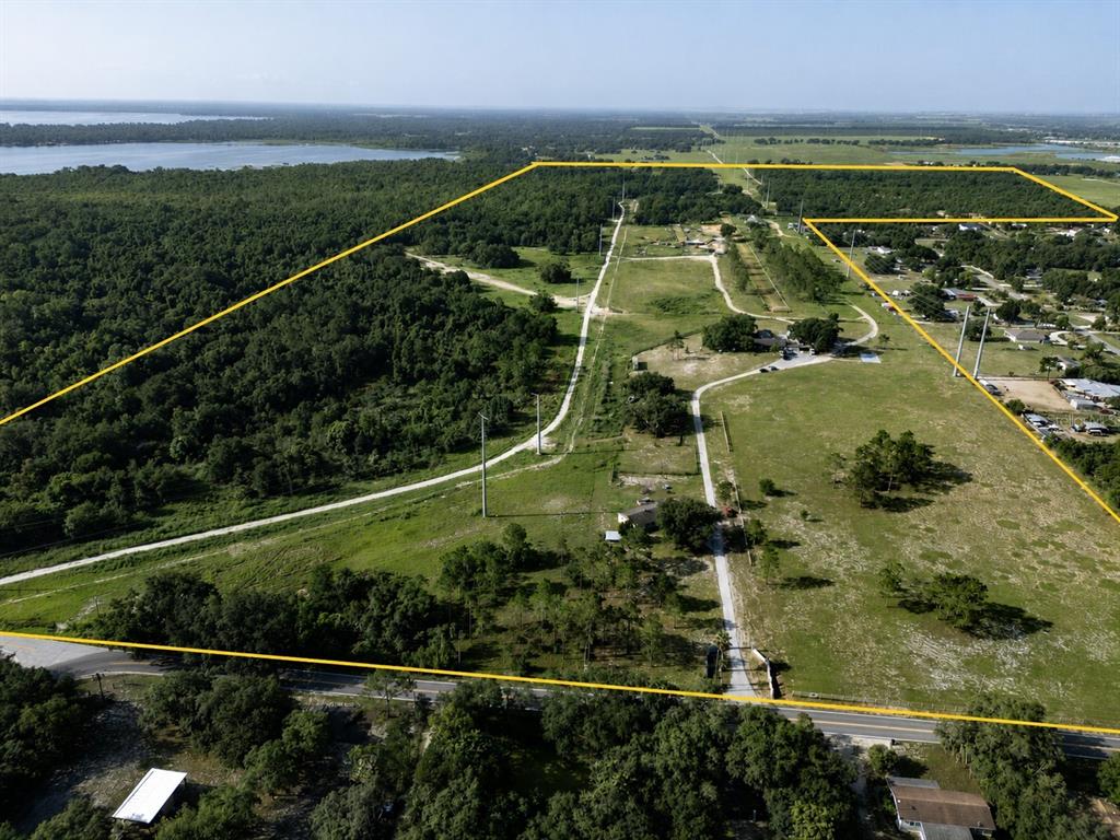 An aerial view shows a large, grassy, partially wooded plot of land outlined in yellow — 5555 E HINSON AVENUE, HAINES CITY, FL