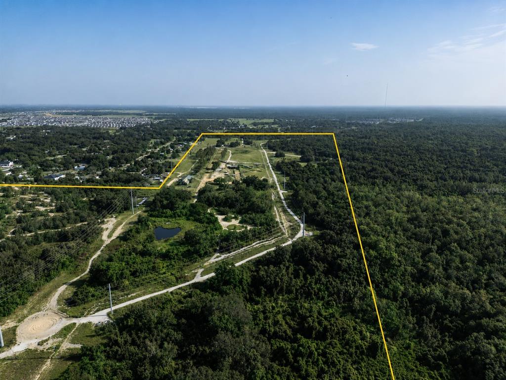 An aerial view shows a large, undeveloped plot of land outlined in yellow — 5555 E HINSON AVENUE, HAINES CITY, FL