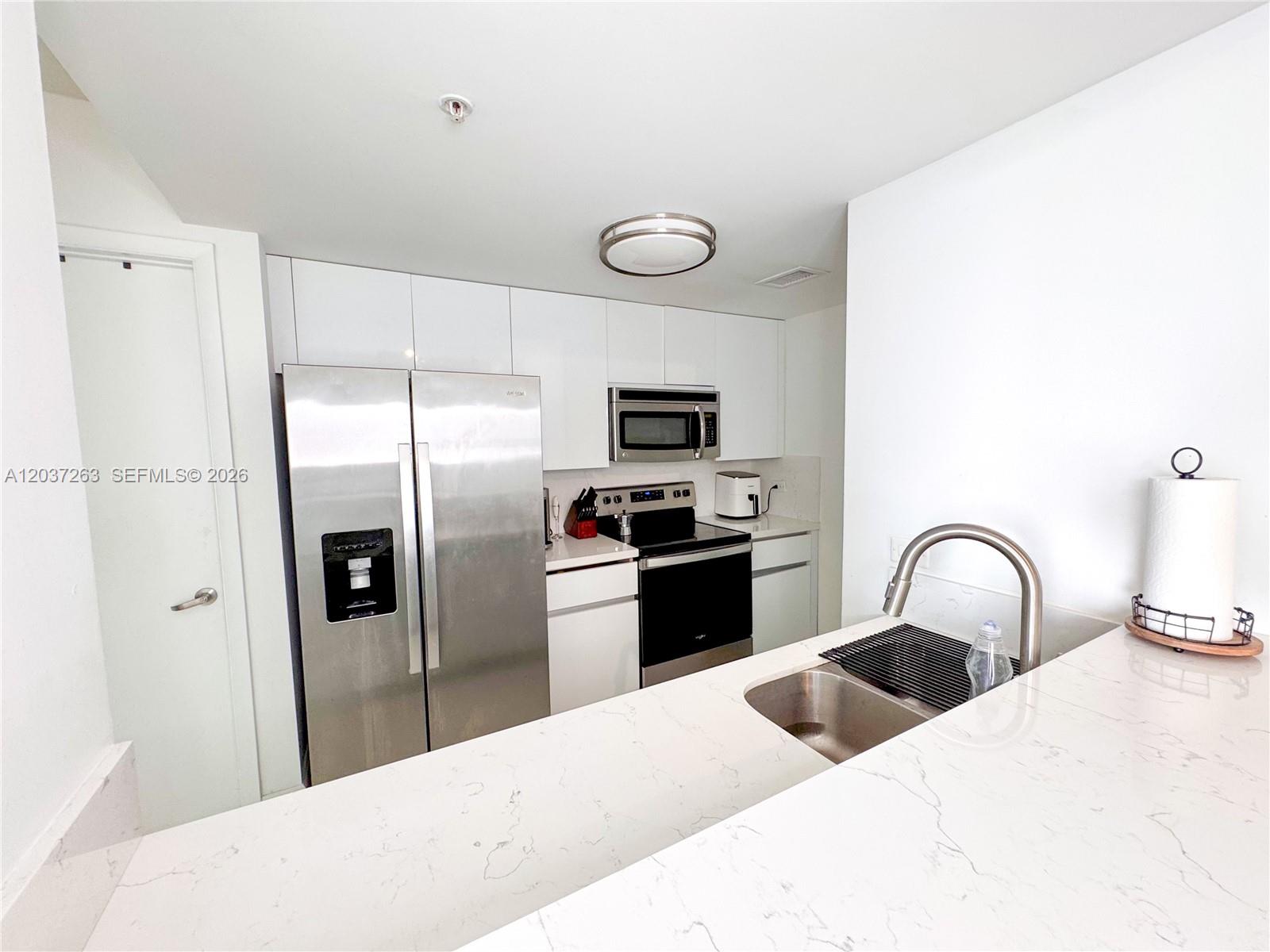 A modern kitchen features white cabinets, stainless steel appliances, and a white marble countertop — 1861 NW S River Dr # 1501, Miami FL 33125, MIAMI, FL
