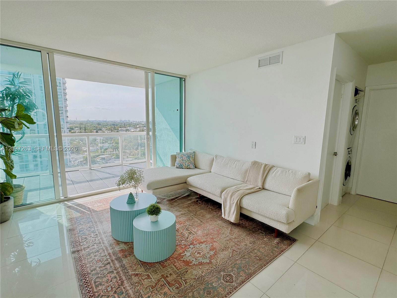 A living room features a white sectional sofa, two blue coffee tables, and a balcony view — 1861 NW S River Dr # 1501, Miami FL 33125, MIAMI, FL