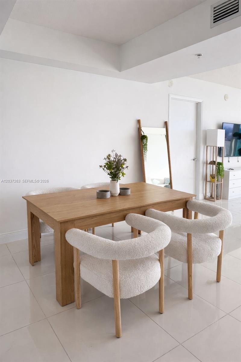 A dining room features a wooden table, four white textured chairs, and a floor mirror — 1861 NW S River Dr # 1501, Miami FL 33125, MIAMI, FL