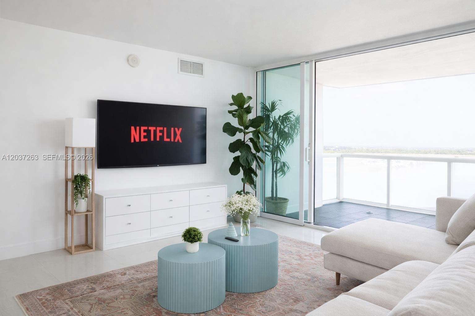 A modern living room features a wall-mounted television, white media console, and blue coffee tables — 1861 NW S River Dr # 1501, Miami FL 33125, MIAMI, FL