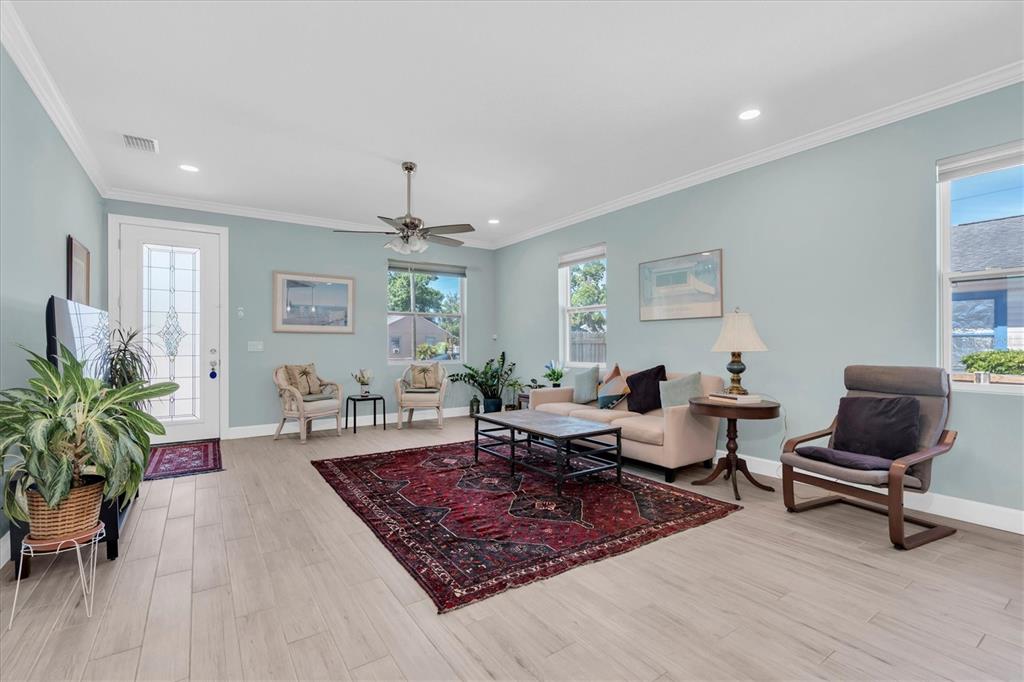 A living room with light blue walls, wood-look tile flooring, and a large red rug — 3069 19TH AVENUE S, ST PETERSBURG, FL
