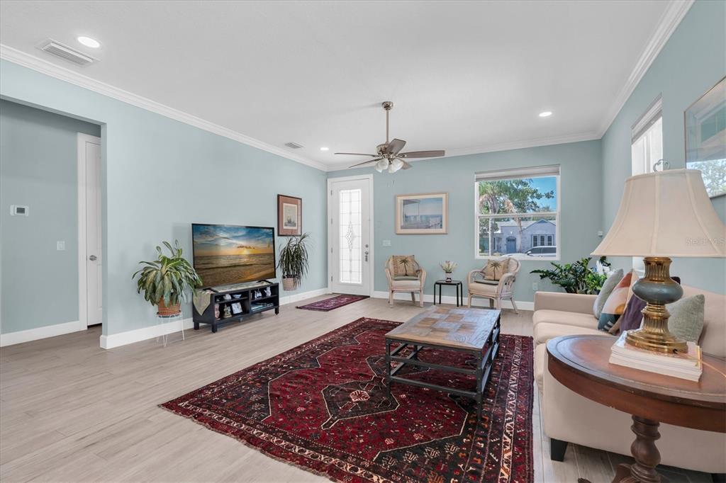 A living room features light blue walls, wood-look flooring, a large area rug, and furniture — 3069 19TH AVENUE S, ST PETERSBURG, FL