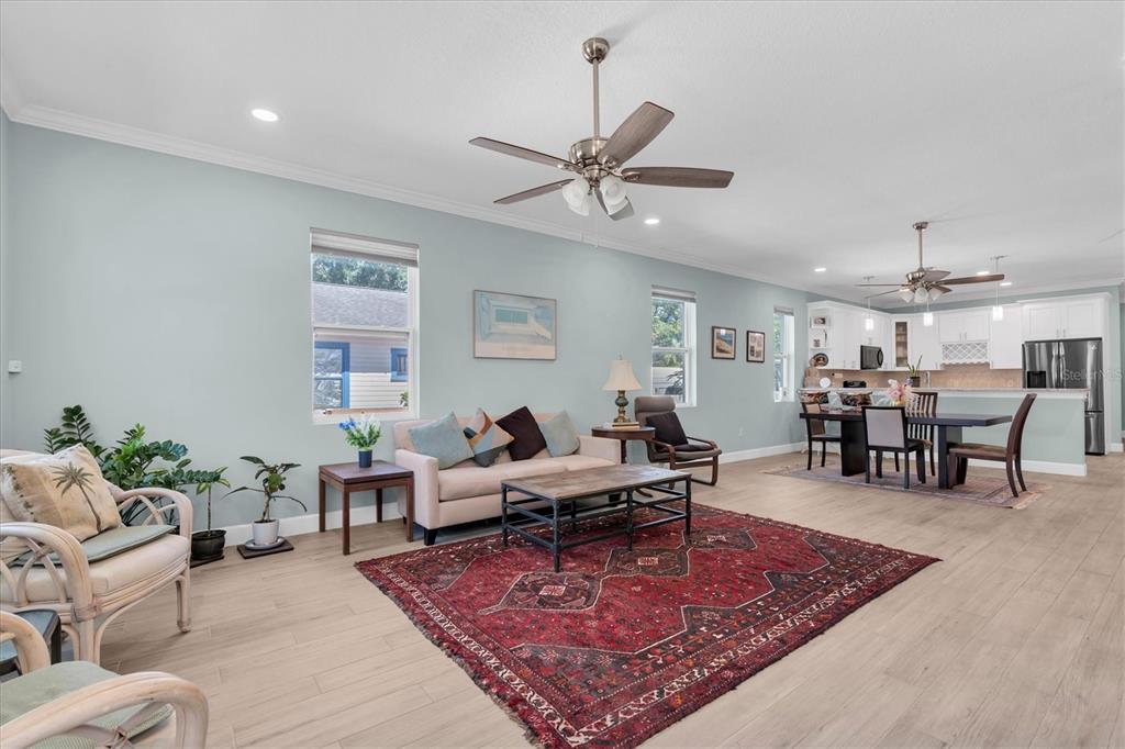 An open-concept living and dining area features light blue walls, wood-look flooring, and ceiling fans — 3069 19TH AVENUE S, ST PETERSBURG, FL