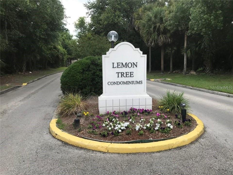 A white monument sign for Lemon Tree Condominiums stands in a landscaped traffic island — 2512 LEMON TREE LANE UNIT 3C, ORLANDO, FL