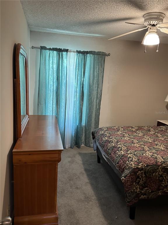 A bedroom features a wooden dresser with a mirror, a bed, and teal curtains — 2512 LEMON TREE LANE UNIT 3C, ORLANDO, FL
