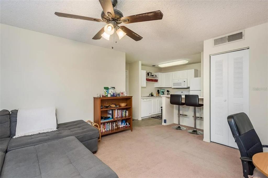 A living room with a gray sectional sofa, a wooden bookshelf, and an open kitchen — 4107 CHATHAM OAK COURT UNIT 313, TAMPA, FL