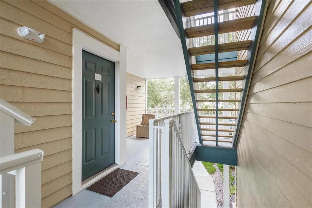 An exterior view of an apartment entrance with a dark door and adjacent wooden stairs — 4107 CHATHAM OAK COURT UNIT 313, TAMPA, FL