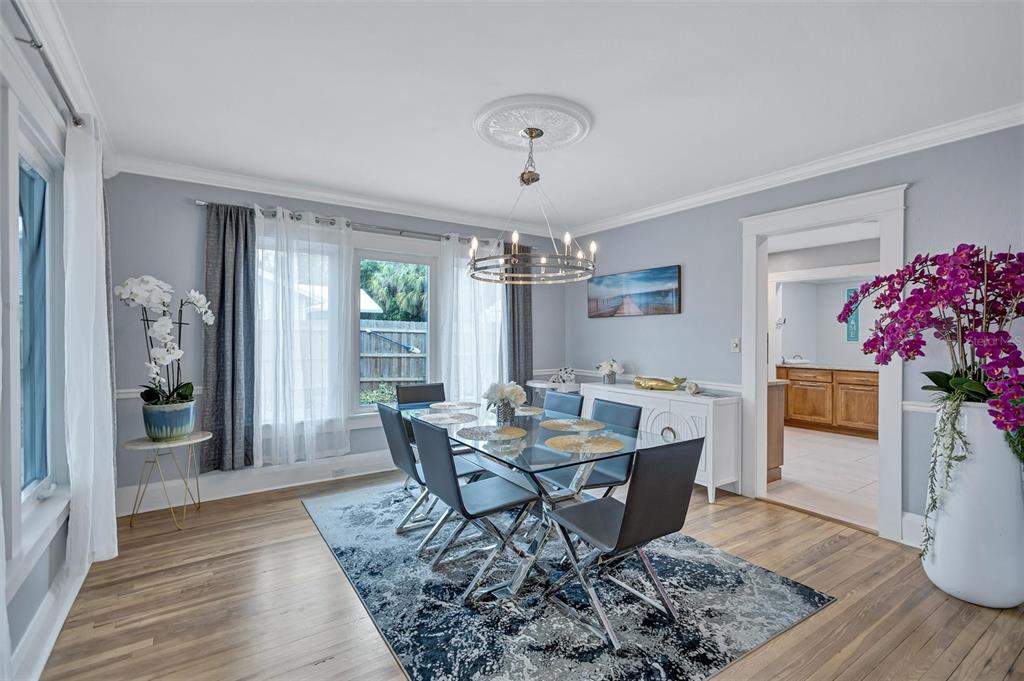 A dining room features a glass table, modern chairs, a chandelier, and hardwood floors — 206 20TH STREET W, BRADENTON, FL