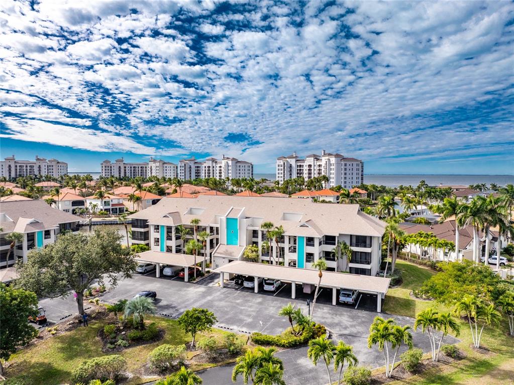 An aerial view shows a multi-story apartment building with covered parking and surrounding palm trees — 3265 SUGARLOAF KEY ROAD UNIT 43B, PUNTA GORDA, FL