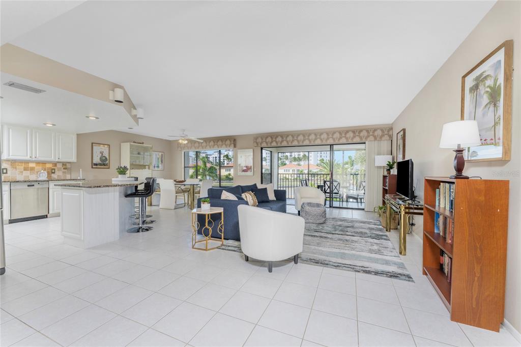 An open-concept living and dining area features white tile floors, a kitchen island, and balcony access — 3265 SUGARLOAF KEY ROAD UNIT 43B, PUNTA GORDA, FL
