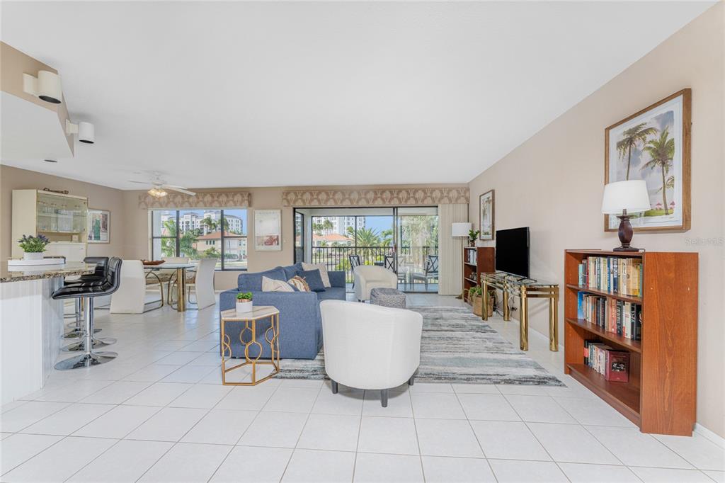 A bright, open-concept living and dining area features tile flooring, a blue sofa, and balcony — 3265 SUGARLOAF KEY ROAD UNIT 43B, PUNTA GORDA, FL
