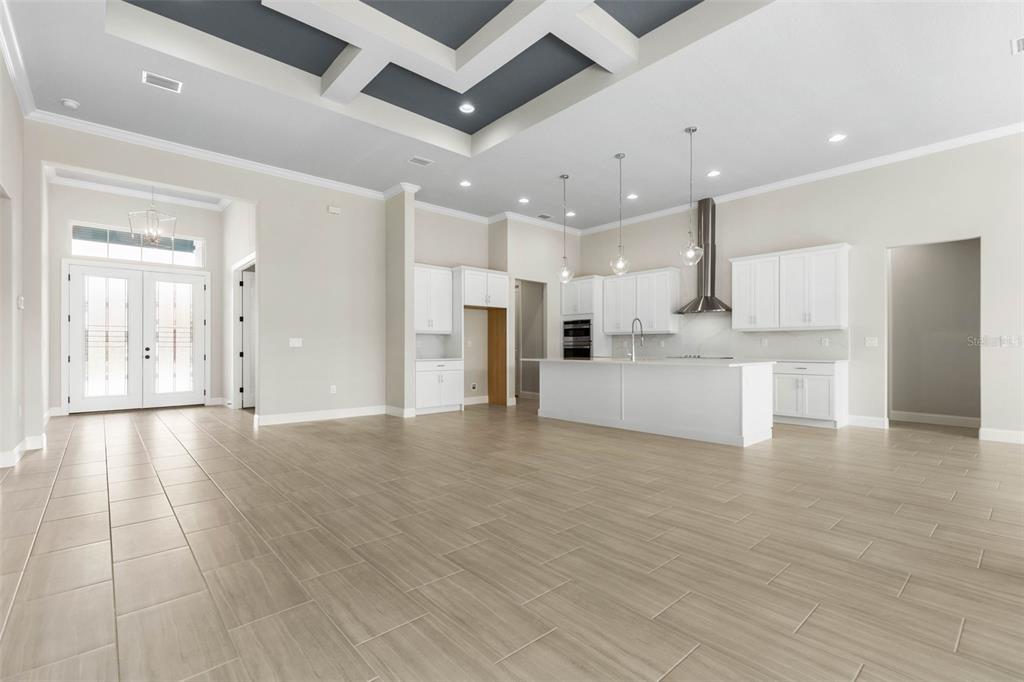 An open-concept kitchen and living area features white cabinetry, a central island, and tile flooring — 103 HERON DRIVE, PALM COAST, FL