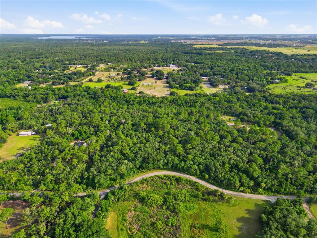 An aerial view shows a winding road cutting through a dense forest and open fields — HORSESHOE CREEK ROAD, DAVENPORT, FL