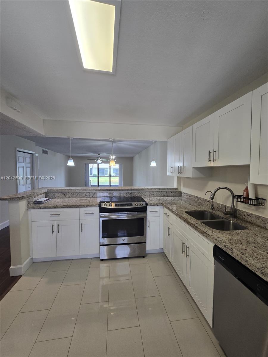 A kitchen features white cabinets, granite countertops, stainless steel appliances, and tile flooring — 16581 Blatt Blvd # 104, Weston FL 33326, WESTON, FL