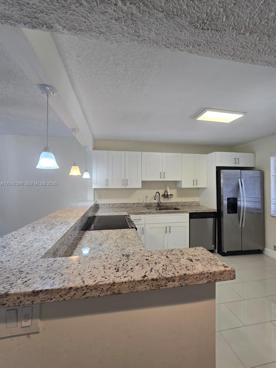A kitchen features white cabinets, granite countertops, stainless steel appliances, and a breakfast bar — 16581 Blatt Blvd # 104, Weston FL 33326, WESTON, FL
