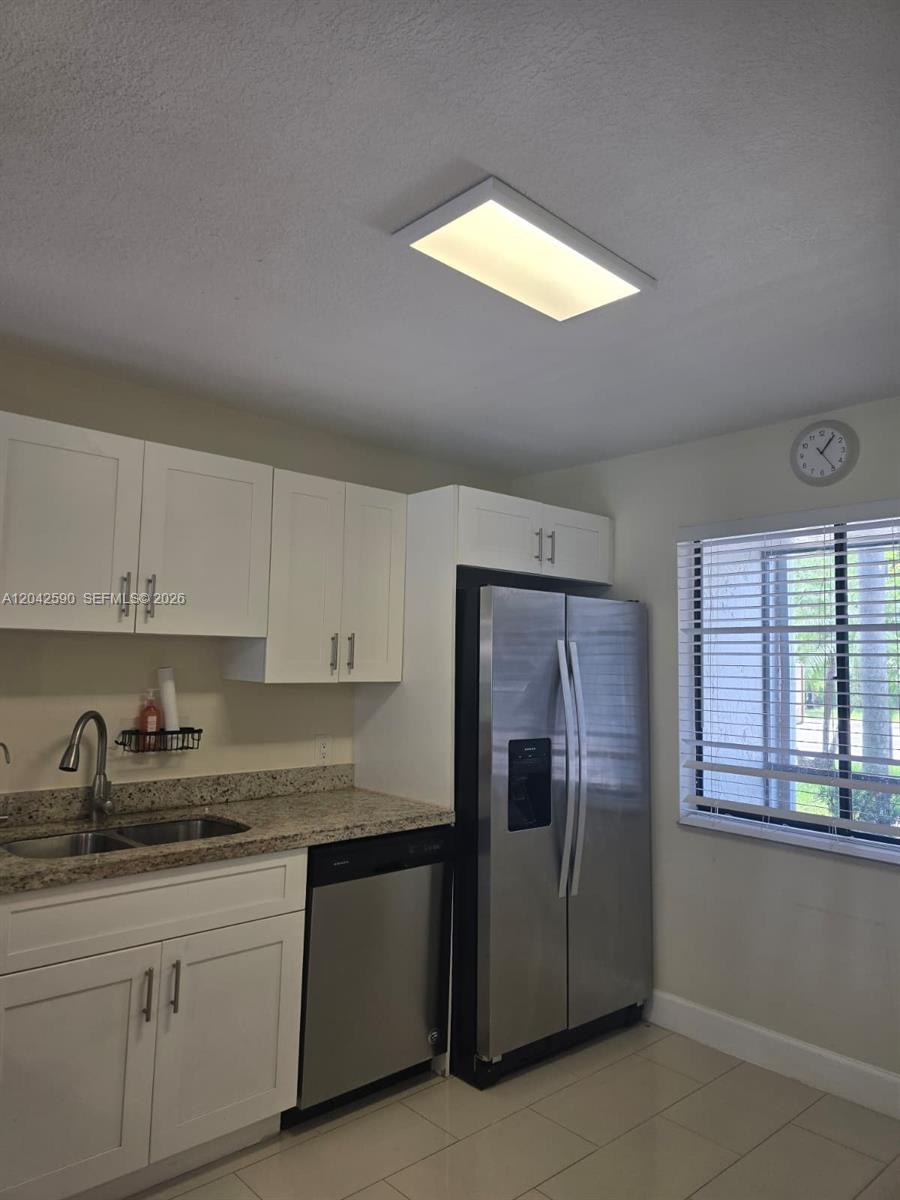 A kitchen features white cabinets, granite countertops, stainless steel appliances, and a rectangular ceiling light — 16581 Blatt Blvd # 104, Weston FL 33326, WESTON, FL