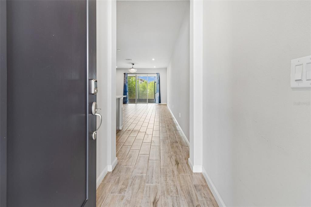 A view through an open front door reveals a hallway with tile flooring leading outside — 4286 CLOUD HOPPER WAY, LUTZ, FL