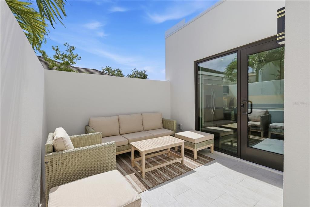 A modern outdoor patio features a wicker sofa, matching chairs, and a coffee table — 1558 4TH STREET UNIT 216, SARASOTA, FL