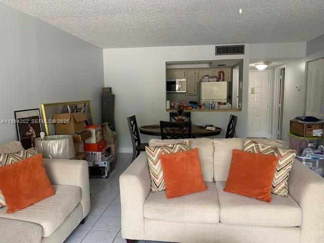 A living room with beige sofas and orange pillows opens to a dining area and kitchen — 5530 NW 44th St # 111C, Lauderhill FL 33319, LAUDERHILL, FL
