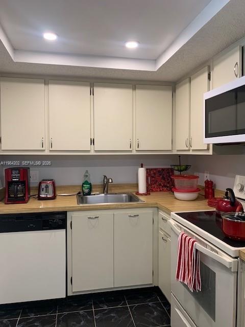 A kitchen features off-white cabinets, a stainless steel sink, and black and white flooring — 5530 NW 44th St # 111C, Lauderhill FL 33319, LAUDERHILL, FL