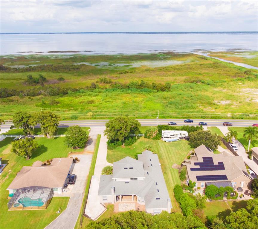 An aerial view shows three houses near a large body of water and a road — 1380 E LAKE SHORE BOULEVARD, KISSIMMEE, FL