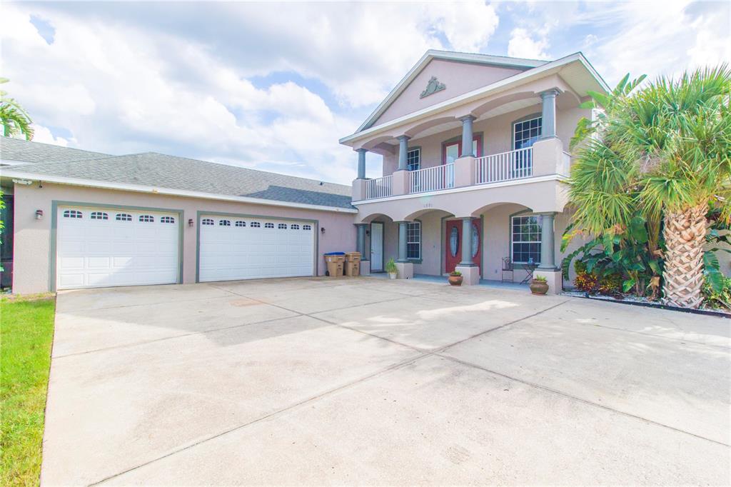 A two-story house with a large concrete driveway, a three-car garage, and a palm tree — 1380 E LAKE SHORE BOULEVARD, KISSIMMEE, FL