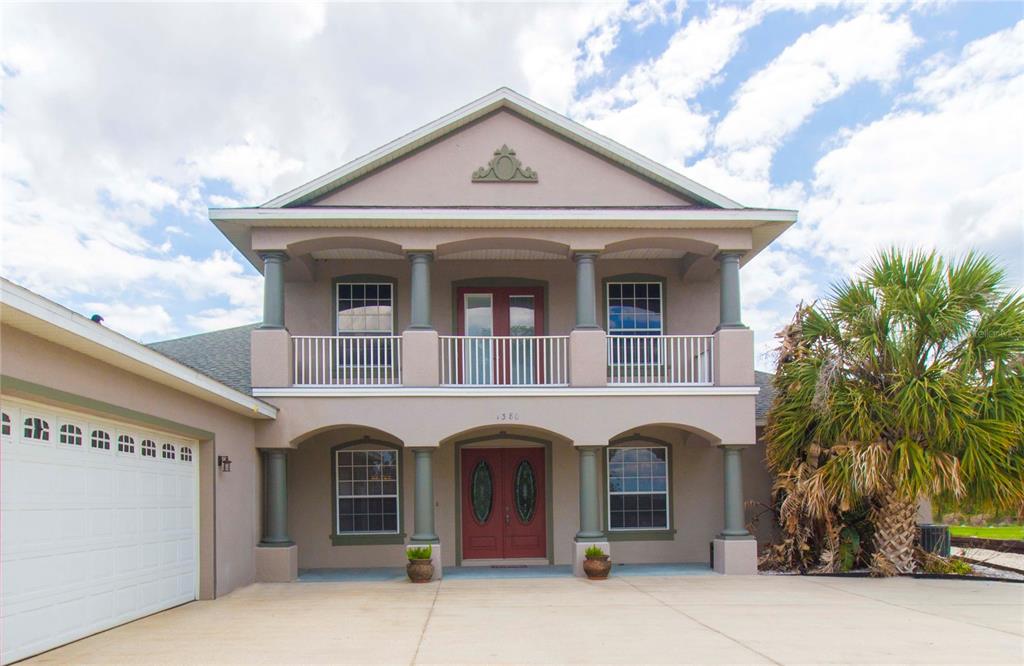A two-story house with a beige stucco exterior, a front balcony, and a double garage — 1380 E LAKE SHORE BOULEVARD, KISSIMMEE, FL