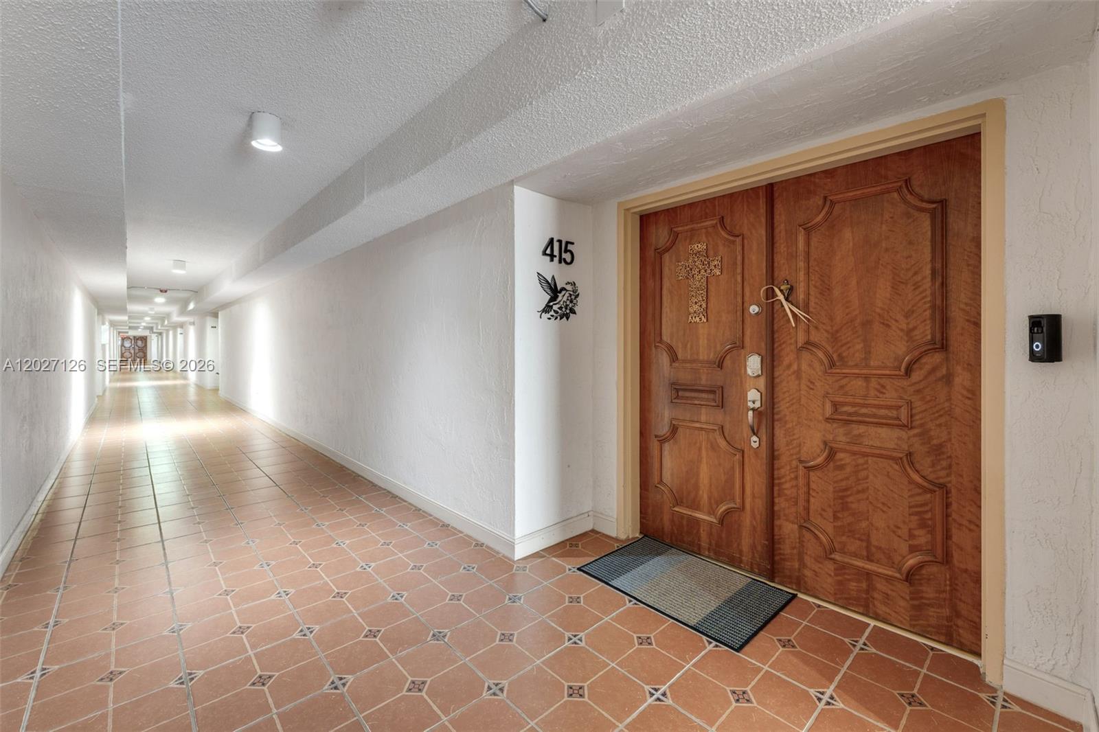 A long hallway with tiled flooring leads to a double wooden door labeled 415 — 1350 SW 122nd Ave # 415, Miami FL 33184, MIAMI, FL