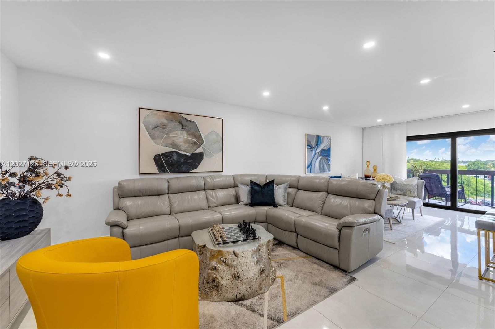 A living room features a grey sectional sofa, a yellow armchair, and a tree-stump coffee table — 1350 SW 122nd Ave # 415, Miami FL 33184, MIAMI, FL