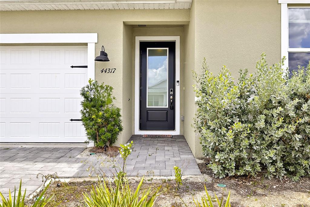 The exterior of a home features a black front door, a garage, and landscaping — 44317 TIMBERLAND TERRACE, PUNTA GORDA, FL
