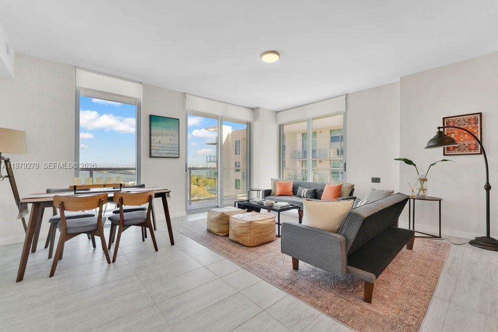 A modern living and dining area features floor-to-ceiling windows with a balcony and water view — 3900 Biscayne Blvd # 1101, Miami FL 33137, MIAMI, FL