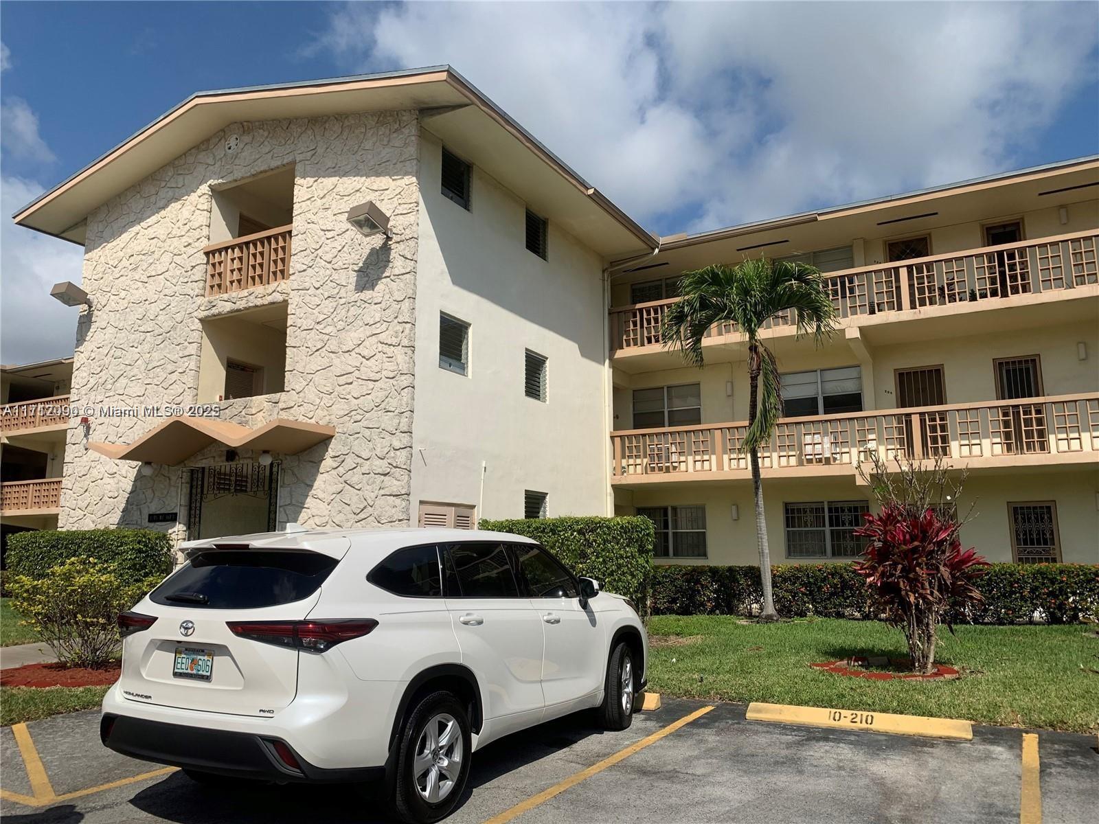 A white SUV is parked in front of a multi-story apartment building with stone siding — 1395 NE 167th St # 209, Miami FL 33162, MIAMI, FL