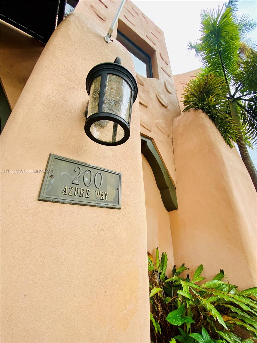 A wall-mounted outdoor light fixture hangs above a metal address plaque on a stucco exterior — 200 Azure Way, Miami Springs FL 33166, MIAMI SPRINGS, FL