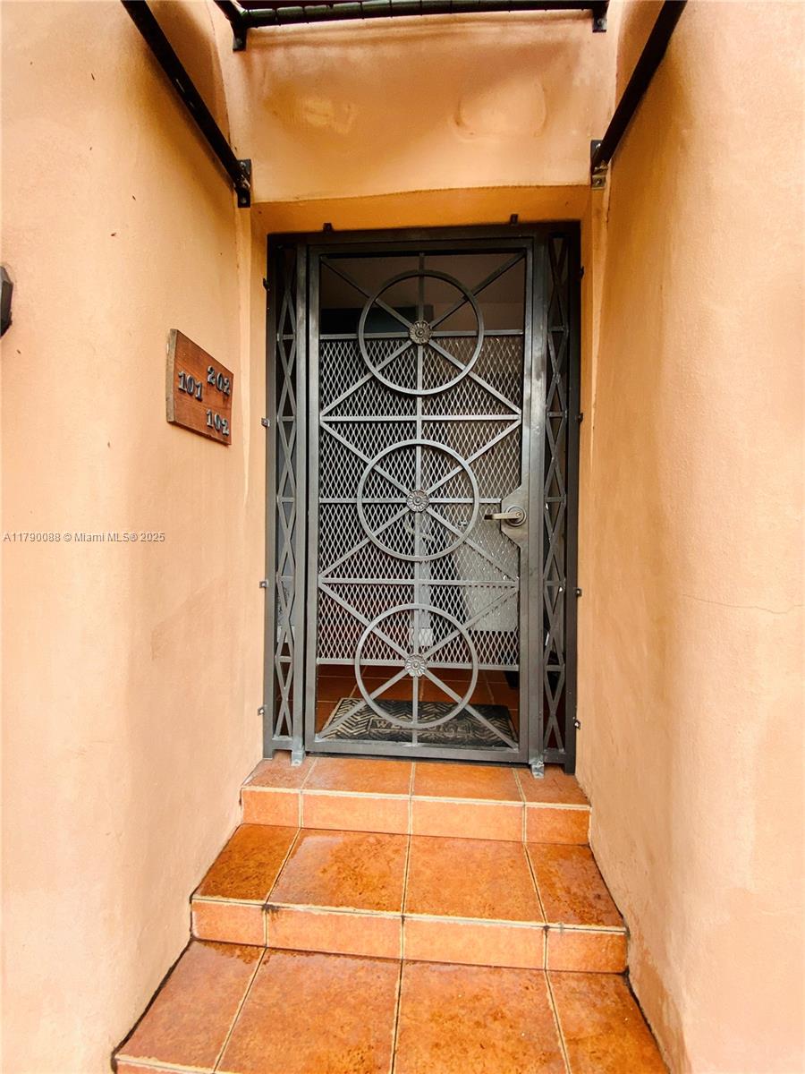 A metal security door leads to an entrance with terracotta-tiled steps and exterior walls — 200 Azure Way, Miami Springs FL 33166, MIAMI SPRINGS, FL
